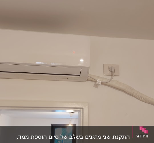 מזגן קיר לבן עם צינור חיבור לקיר